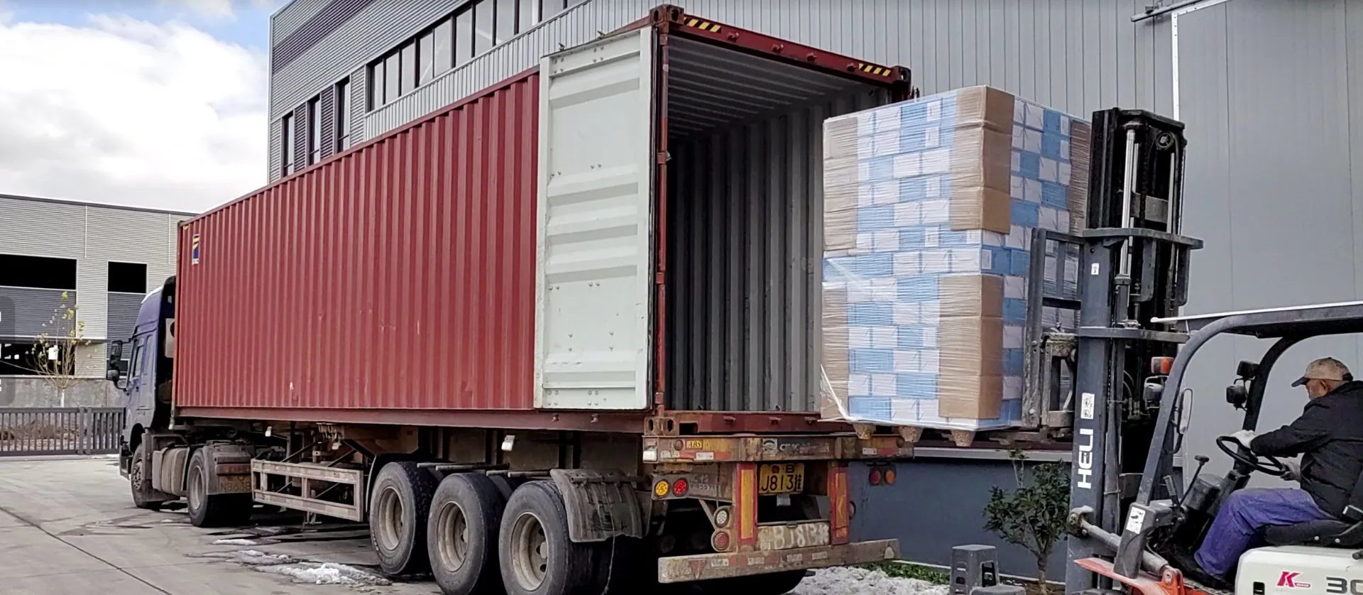 Forklift loading pallets of cat litter into shipping container at Gormeet factory